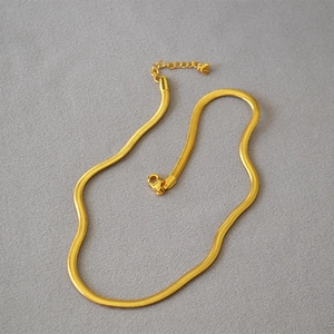 Detailed view of golden flat snake chain necklace with lobster clasp and adjustable link