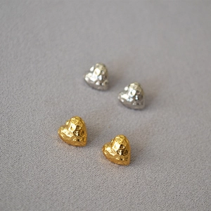 Detail of gold and silver heart stud earrings with a unique hammered metal texture finish