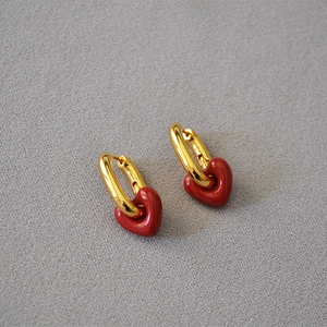 Fashionable gold hoop earrings featuring vibrant red enamel heart pendants in a minimalist style
