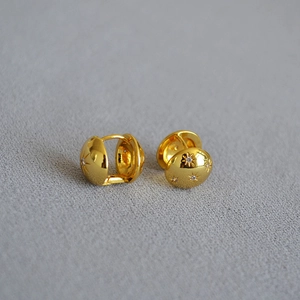 Elegant gold plated North Star huggie earrings with cubic zirconia on grey background