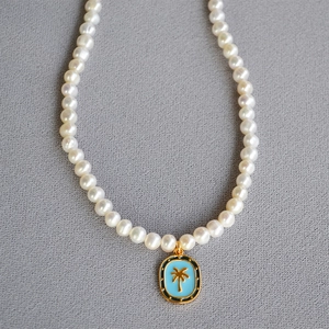Detailed view of freshwater pearl necklace with a blue enamel palm tree pendant