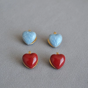 Detailed macro view of heart-shaped enamel gold earrings in blue marble and red colors