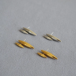 Gros plan sur les boucles d'oreilles clous dorées et argentées au design géométrique moderne