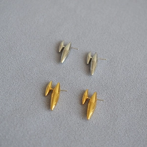 Détail macro de boucles d'oreilles clous en laiton doré et argenté au fini poli miroir