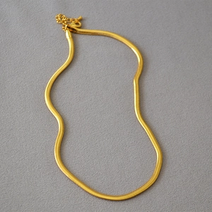 Detailed view of golden flat snake chain necklace with lobster clasp and floral charm