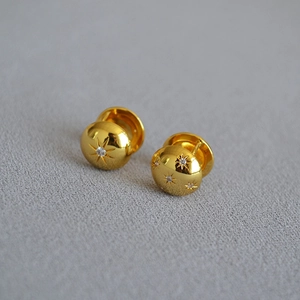 Macro shot of gold-plated North Star earrings featuring zircon studs on a textured base