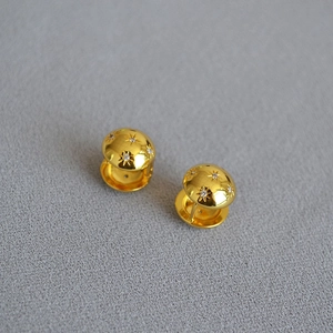 Detail of gold-plated North Star earrings with sparkling cubic zirconia on gray fabric