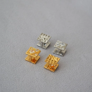 Detail of square gold and silver earrings with irregular textures and cubic zirconia