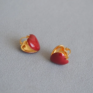 Macro view of gold-plated brass earrings with red heart enamel and polished finish