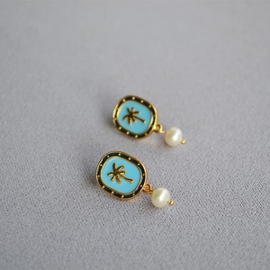 Detailed macro view of tropical palm tree enamel earring with a white round pearl drop
