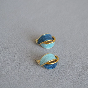 Dettaglio di orecchini vintage in ottone dorato con smalto marmorizzato blu e perno argento