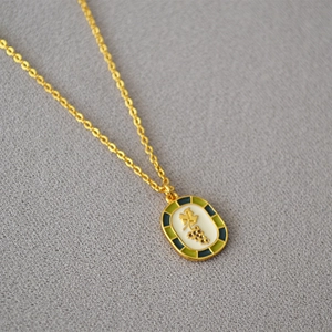 Detailed macro view of vintage gold pendant with white enamel and green blue borders