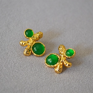 Retro court style irregular gold texture earrings with green gemstones on grey fabric