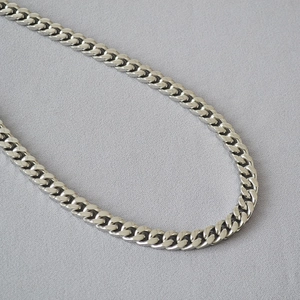 Close-up of polished silver-tone stainless steel curb chain links with industrial texture