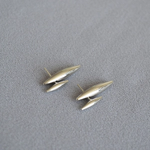 Détail de boucles d'oreilles géométriques en argent au design métallique profilé poli