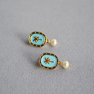 Detail of gold coconut tree earrings with blue enamel and dangling round pearl pendants