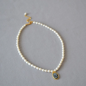 Detail of vintage freshwater pearl necklace with an oval relief cameo pendant and gold clasp