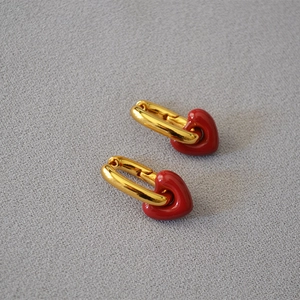 Detail of gold U-shaped hoop earrings with handmade red enamel heart pendants