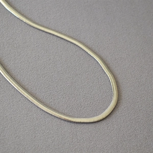 Detailed macro view of the silver snake bone chain showing its woven metal texture