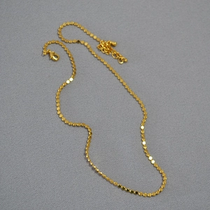 Detailed shot of gold plated necklace with small shiny discs and lobster clasp