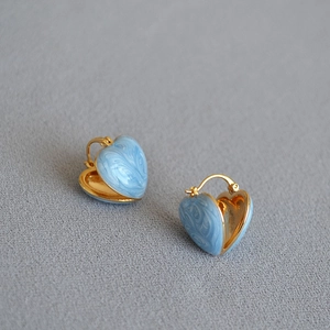 Detail of heart earrings with light blue marble enamel and gold-plated finish
