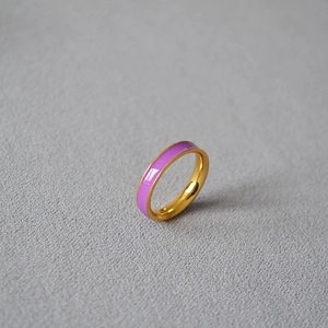 Minimalist gold-plated brass ring with purple enamel inlay on a dark textured background