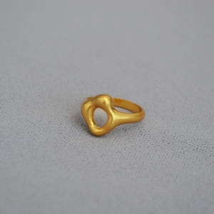 Detail of irregular lava texture gold brass ring with an oval cutout design