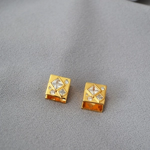 Macro shot of gold-plated geometric square earrings with sparkling cubic zirconia inlay