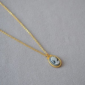 Detail of vintage French style cameo pendant with twisted gold border on a fine chain