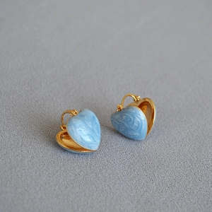 Detail of light blue marble enamel heart earrings on grey fabric background