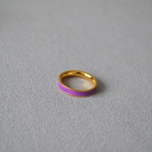 Detail of minimalist gold plated brass ring with purple enamel inlay on gray texture