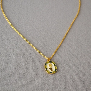Detailed close-up of oval enamel grape pendant on a gold chain necklace with vintage style