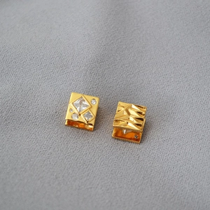 Macro detail of asymmetric gold earrings with cubic zirconia and hammered metal texture