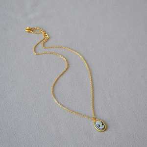Close-up of vintage cameo pendant with gold rope border on delicate link chain necklace