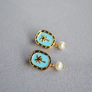 Detail of blue enamel earrings featuring gold coconut trees and hanging pearls