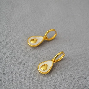 Close-up of gold-plated pear-shaped earrings with mother of pearl and heart detail