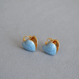 Detail of gold-plated heart earrings with light blue marbled enamel finish