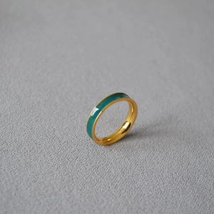 Minimalist gold plated brass ring with green enamel finish on a grey textured background