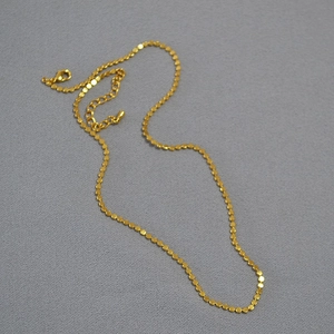 Detail of gold plated necklace showing small round discs with lobster clasp and extender chain