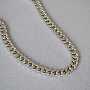 Macro detail of silver punk Cuban link chain with polished stainless steel flat links