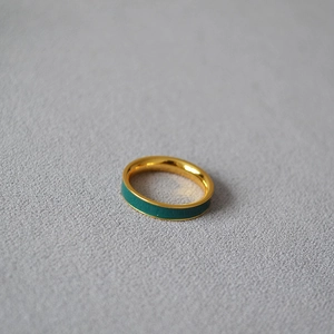 Macro shot of minimalist gold plated brass ring featuring dark green enamel finish