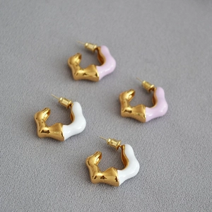 Detail of gold-plated irregular wave C-shape enamel earrings with fluid metal texture