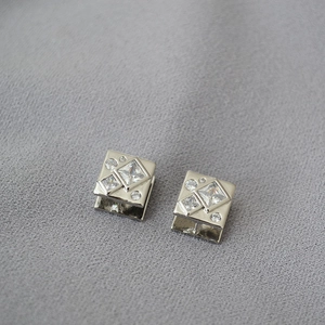 Detail of silver geometric stud earrings featuring square and round cubic zirconia stones