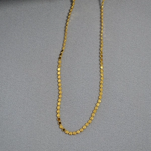 Detailed macro view of delicate gold-plated chain with shiny hexagonal metal discs
