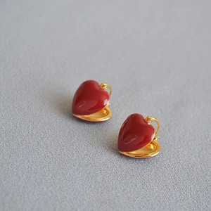 Detailed macro view of red enamel heart drop earrings with gold-plated brass base