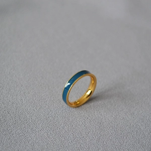 Close-up of a minimalist gold-plated brass ring with deep blue enamel inlay on fabric