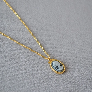 Macro shot of French vintage oval cameo pendant with twisted gold border on a fine chain