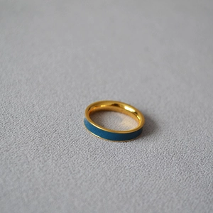 Macro view of a gold-plated brass ring with a deep blue enamel inlay and smooth finish