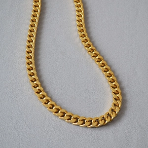 Macro view of gold-plated Cuban link chain showing flat polished metal rings and glossy texture