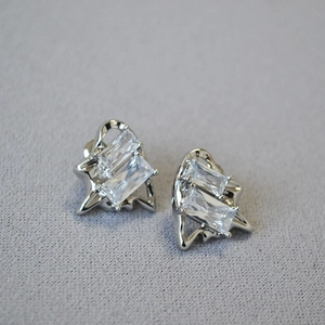 Macro shot of silver stud earrings featuring rectangular zircons and wavy metallic frames